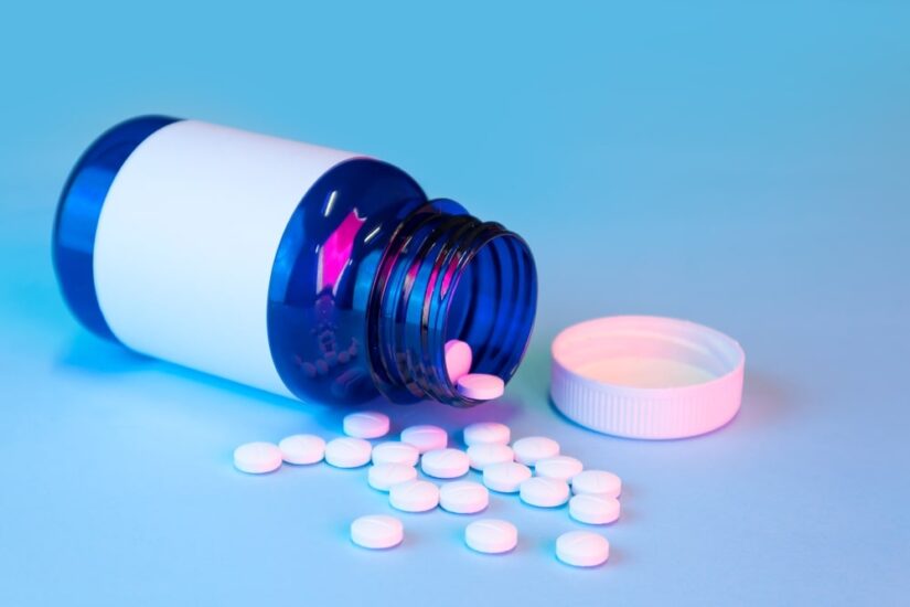 An Opened Pill Bottle Laying On The Table With Pills Spilling Out